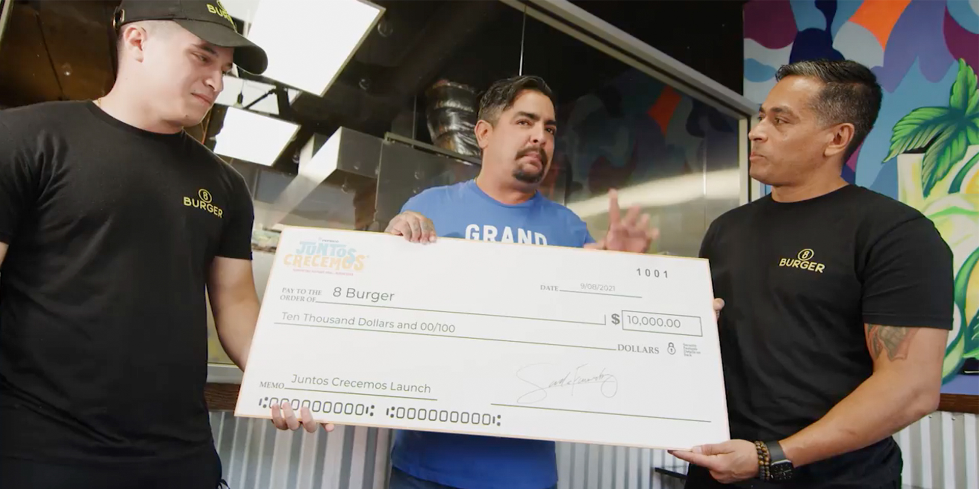 Three men holding a big cheque in a restaurant.