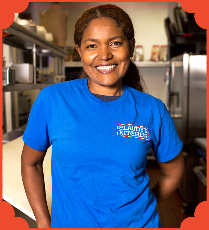 A smiling woman in a blue shirt in her restaurant. 